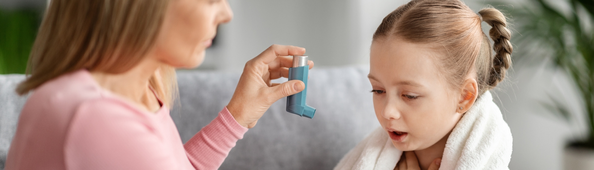 Caring mother giving asthma inhaler to sick child at home